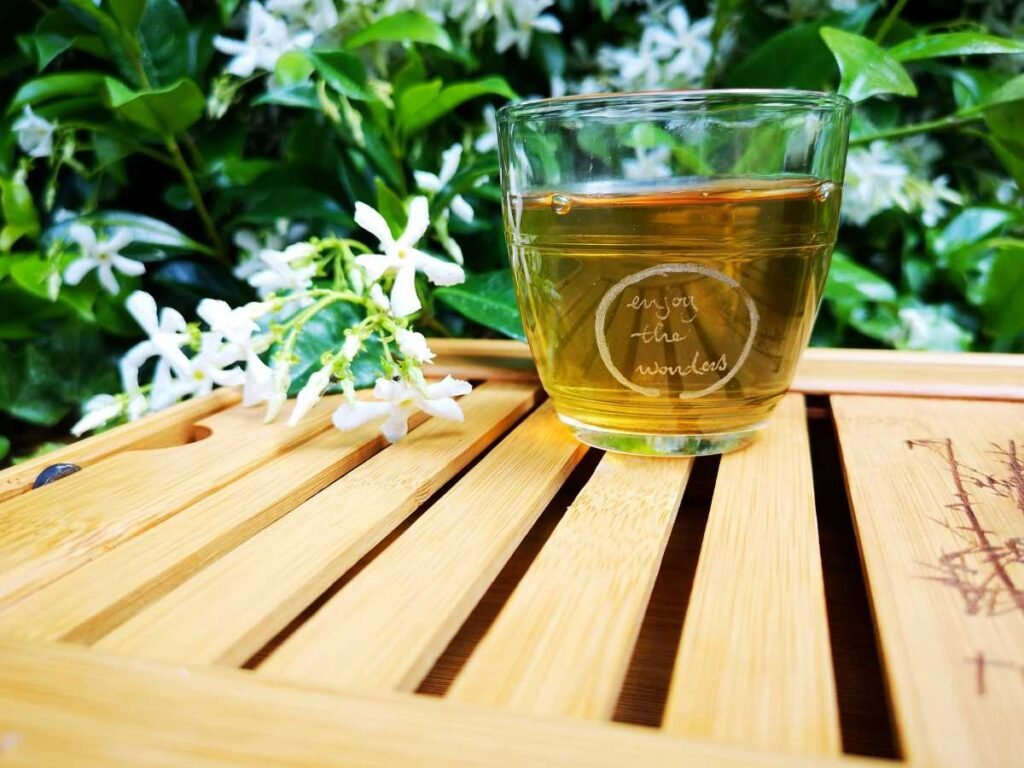 cup of jasmine green tea with jasmine flowers in the background