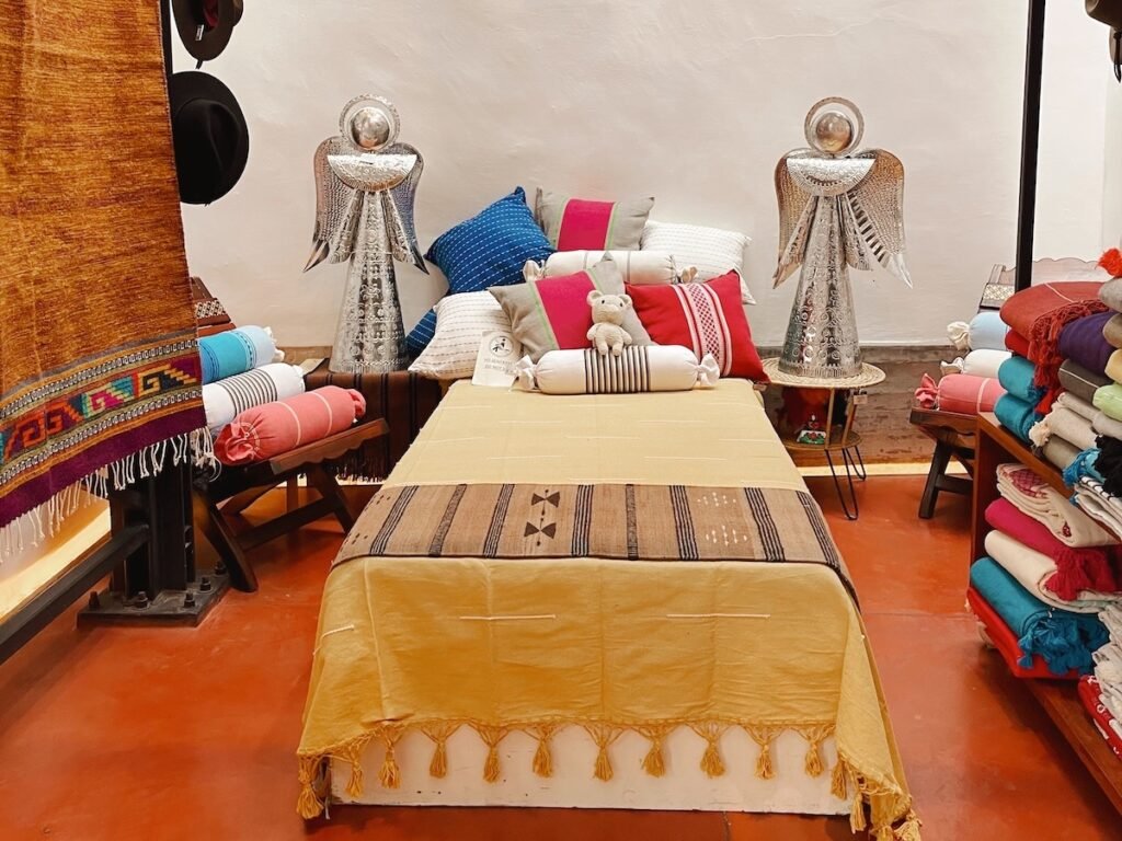 bed covered with a yellow embroidered textile. there are two angels on each side of the bed