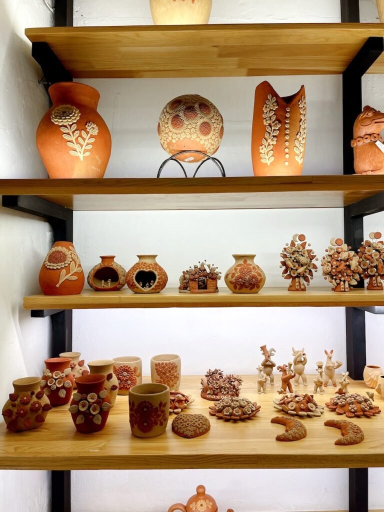 various types and sizes of clay pottery spread on 4 shelves