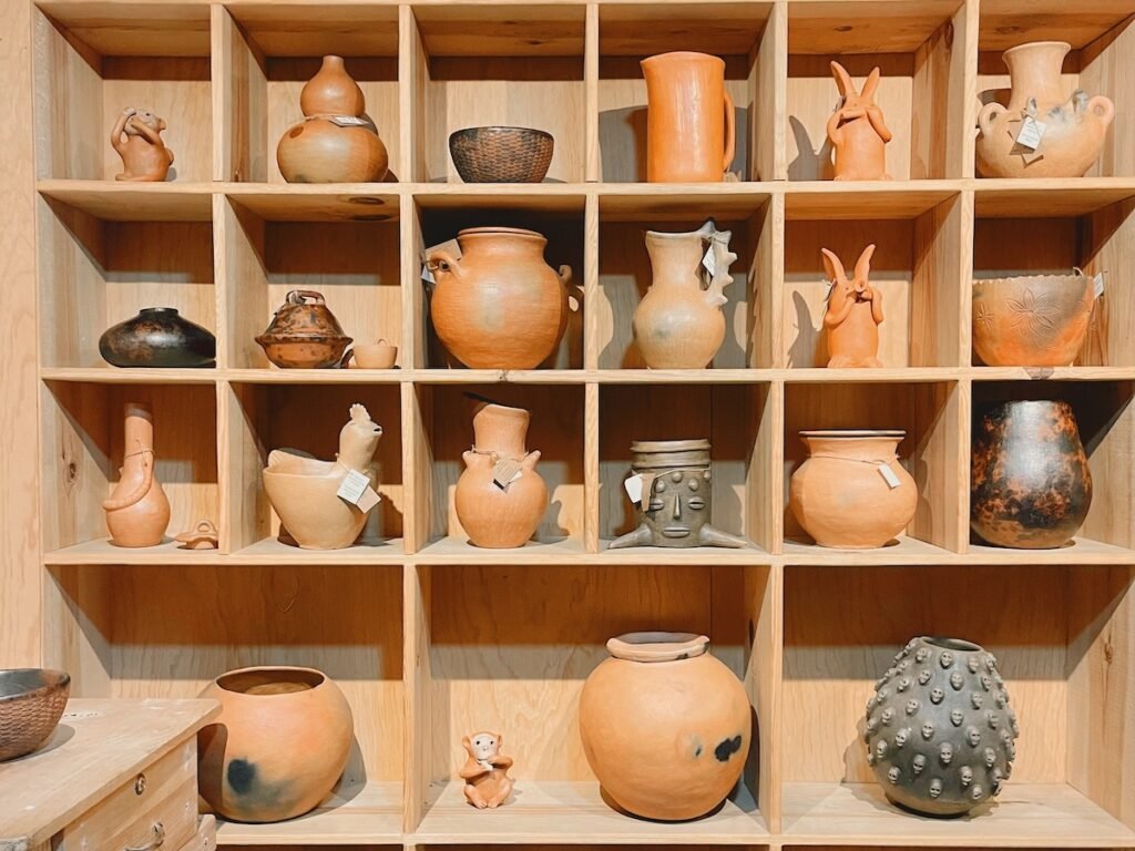 clay pottery of all sizes and shapes, each item is in a square cubicle made of wood shelves