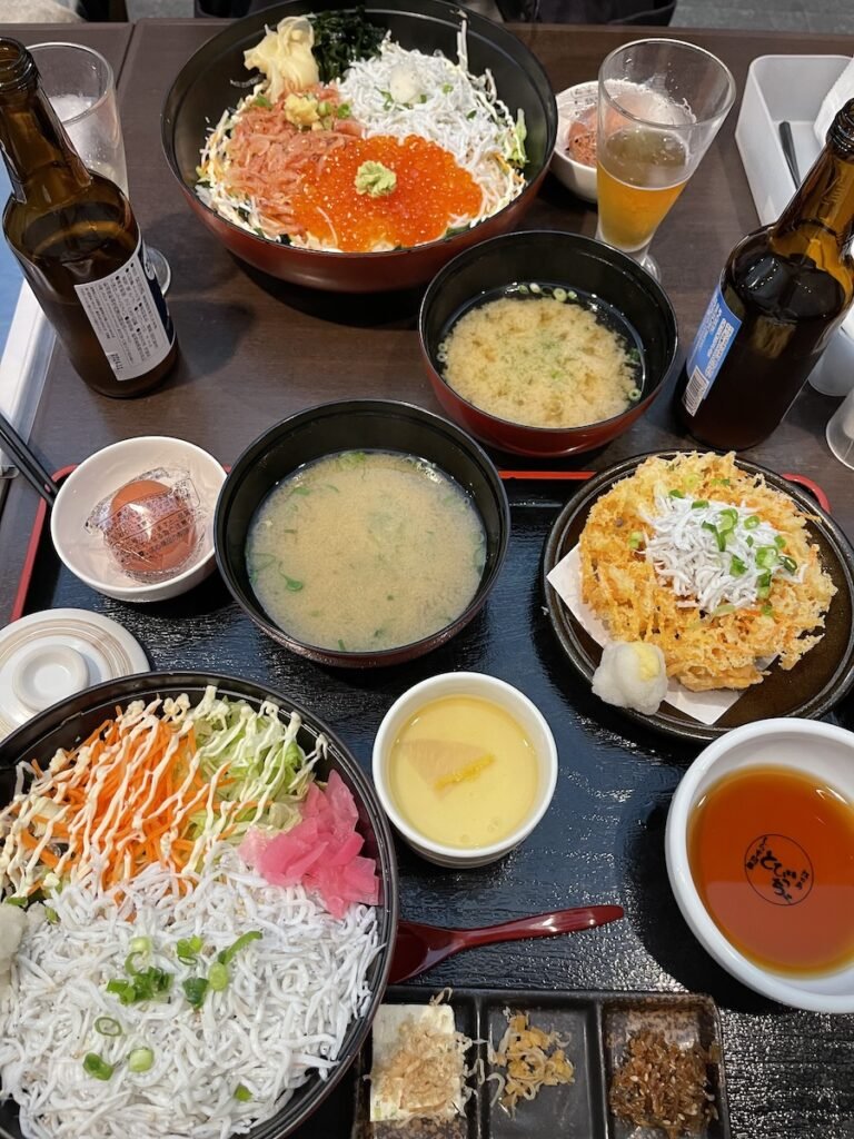 dinner spread at Tobiccho donburi seafood restaurant. two dishes of shirasu, 2 miso soups, and 2 beers