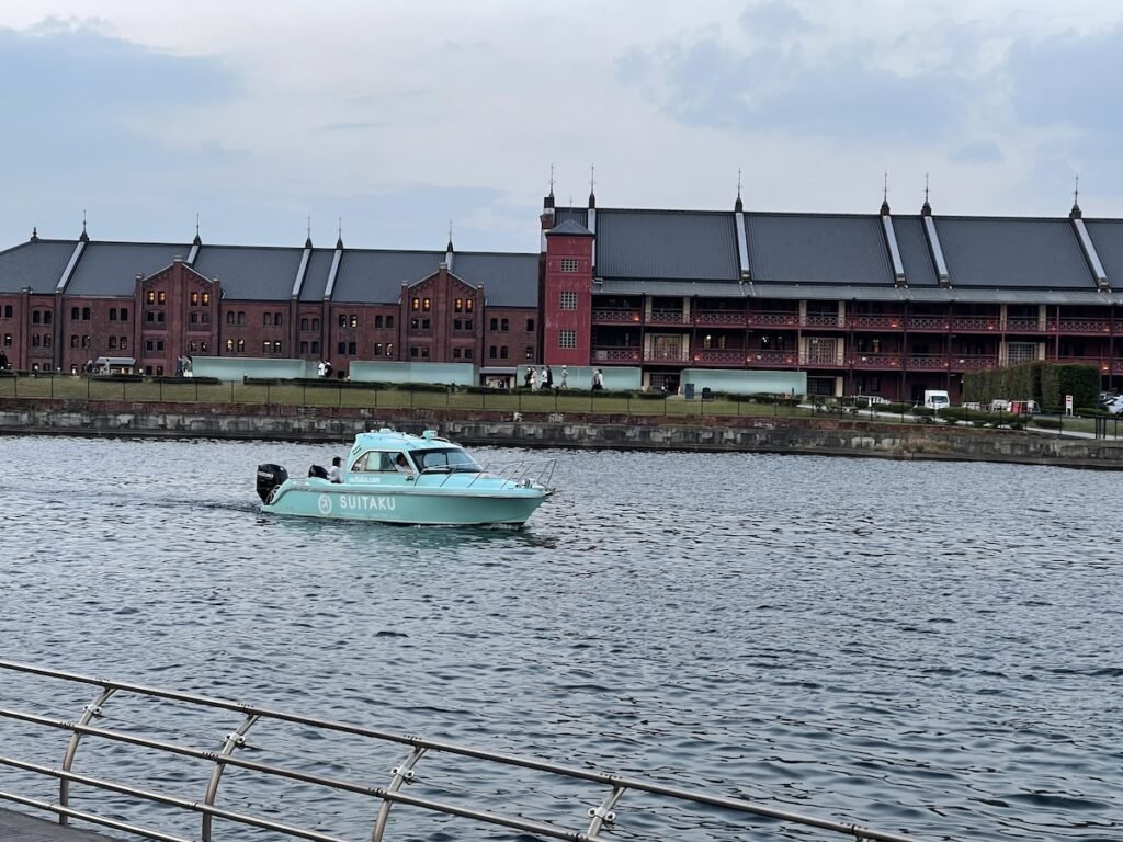 image of yokohama red brick warehouse in the background and a blue boat on the water in the foreground