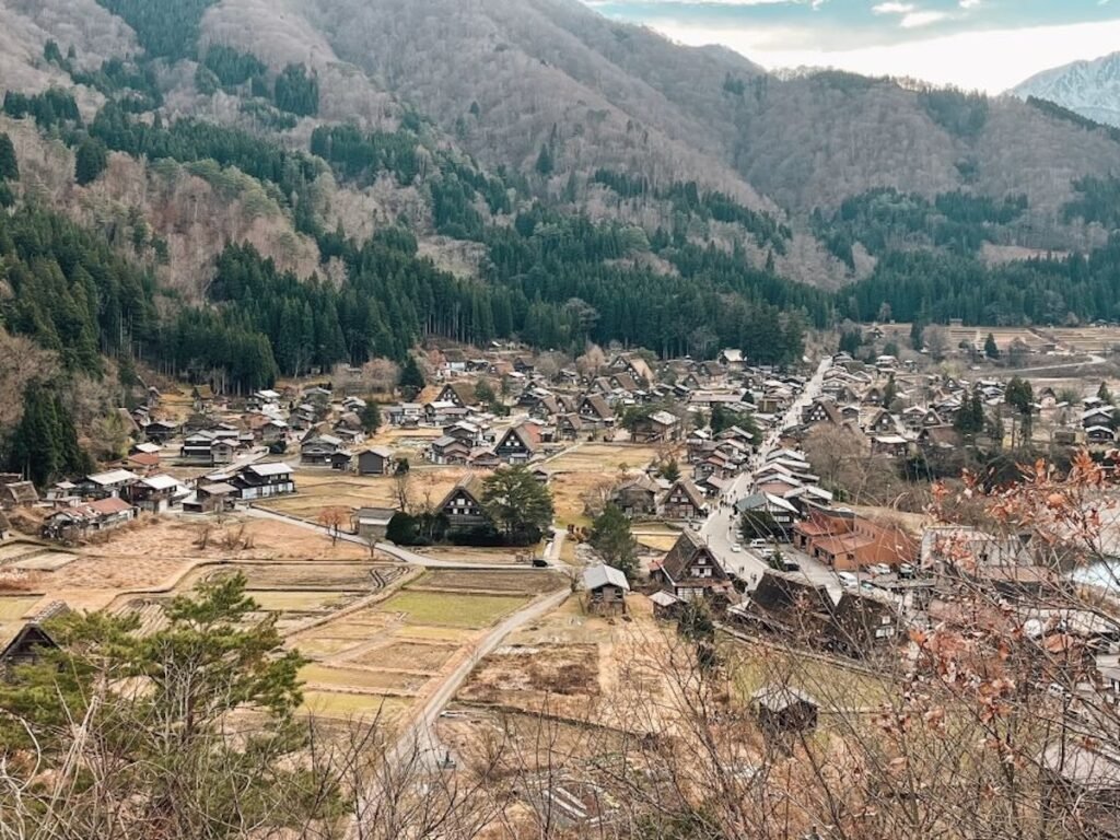 panoramic view of shirakawago thatched roof houses and serene landscape surrounded by mountains and fields