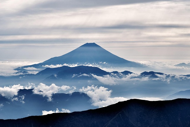 Panoramic view of Mount Fuji reflecting in Lake Kawaguchiko from a scenic viewpoint, with a small red torii gate in the foreground. (Mount Fuji Day Trip)