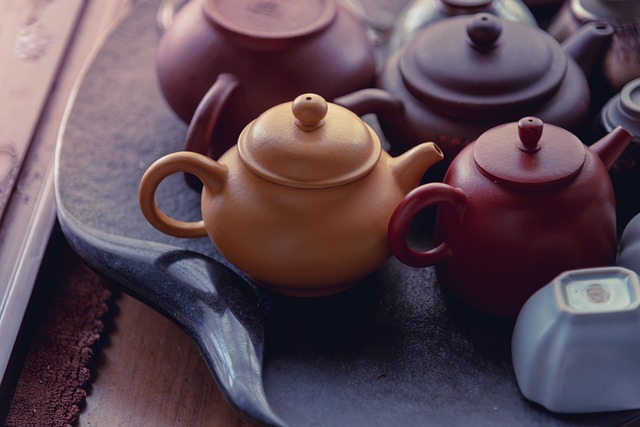A steaming ceramic teapot with a strainer, showing fresh green tea leaves inside.